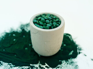Green hawaiian spirulina in tablespoons pills and powder on light white background. Super food, healthy lifestyle, healthy supplements concept