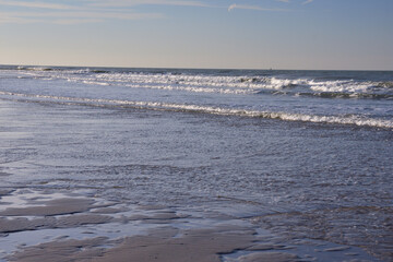 The shore of the sea at low tide, visible sea waves in the distance.