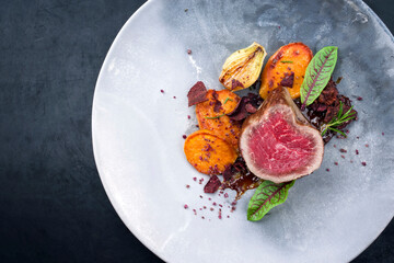 Fried dry aged beef fillet steak natural with potato and vegetable fries offered as overhead view on a modern design plate with copy space left