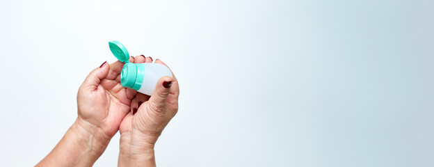 Woman pouring gel or cream into her hand to disinfect them and the coronavirus pandemic. Hand care concept. Banner