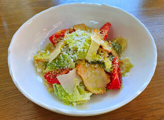 Caesar salad with fried chicken pieces and grated Parmesan cheese on a plate