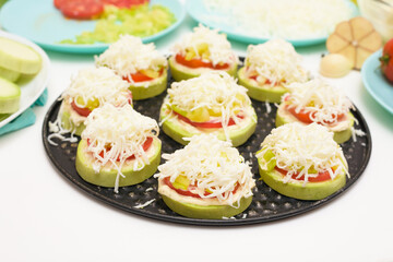 step by step recipe and ingredients for cooking homemade zucchini mini portioned pizza with mozzarella and tomatoes, pepper and garlic. top view on a light background.