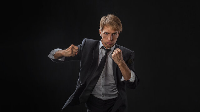 Competition in business, concept. A young man in a suit and tie fights with his fists, an aggressive businessman