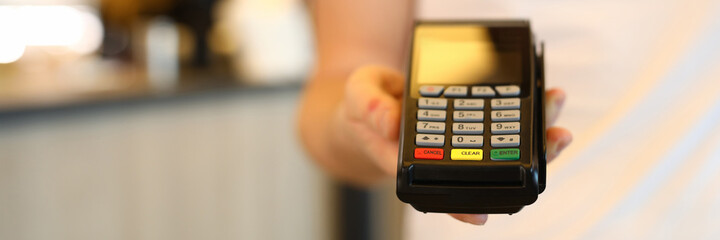 Obraz premium Man holds commercial portable banking terminal. To install wireless terminal for business. Convenient way to make settlements. Terminal payment by card. Effective acquiring offer