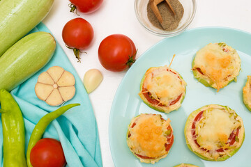 recipe and ingredients for cooking homemade zucchini mini portioned pizza with mozzarella and tomatoes, pepper and garlic. top view on a light background.