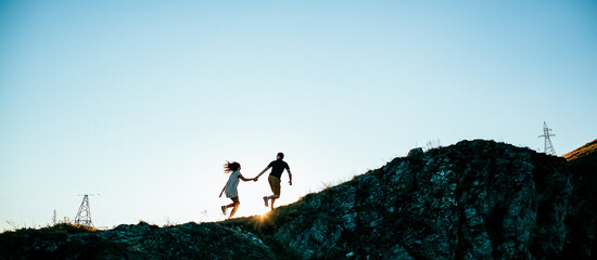 silhouette of a man and a woman in the open air, two young people in nature, silhouette at sunset