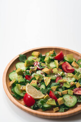 Fresh and healthy summer salad with cucumbers, tomatoes, avocado, arugula, sunflower seeds, lemons and chili flakes. Seasoned with olive oil. White background