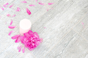 Beautiful pink peony flowers and white candle on light grey stone background with copy space for your text top view. Greeting card, SPA and romantic concept.