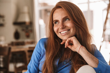 Image of happy ginger woman smiling and looking aside