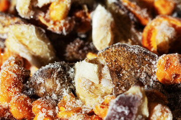 Frozen mushrooms on a gray background. Storage of frozen food. Frozen product. Chanterelles and porcini mushrooms frozen close-up. Top view. Macro.