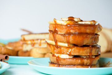 French toast with banana and homemade caramel with cinnamon, Breakfast dessert on a blue plate on a light background