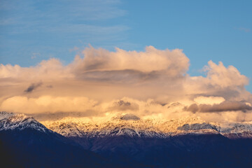 Naklejka na ściany i meble Amazing clouds and blue sky over The Andes Mountains with a golden sunlight, Chile