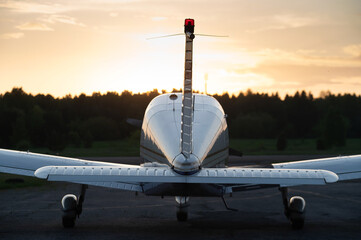 Rear view of a parked small plane on a sunset background. Silhouette of a private airplane landed...