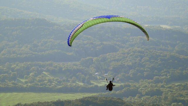 Paragliding soaring through the air, solo paraglider floats peacefully in slow motion