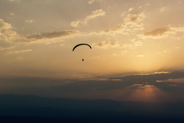 Paraglider flies in the clouds at sunset, background, blur