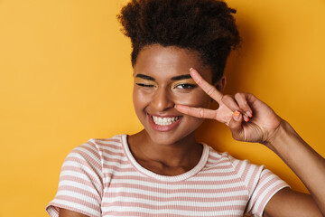 Image of african american woman gesturing peace sign and winking
