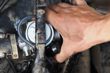 Man replacing the scooter's carburetor with a new one.
