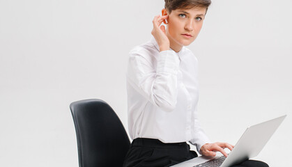  close portrait of a young businesswoman, which uses wireless headphones for a video call. white background in studio. online business meeting concept