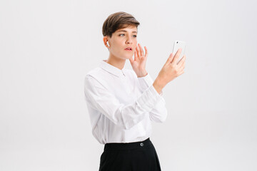 a young woman uses wireless headphones for a video call. white background in studio. online business meeting concept