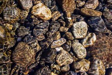Pebble stone underwater close-up in sunlight. Natural background
