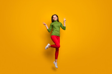 Fototapeta na wymiar Full size photo of positive cheerful girl have winter vacation weekends jump make v-sign wear casual style clothing isolated over yellow color background