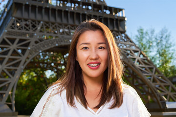 Asian girl in white T-shirt with braces looking at the camera and smiling, blurred background