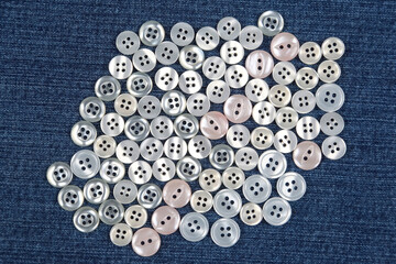 Plastic shiny buttons for clothes on a fabric background. Fashion and clothing. Factory industry.