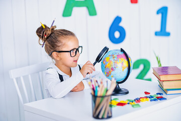Happy smiling pupil at the desk. Child in the class room with pencils, books. Kid girl from primary school. first day of fall. Back to school.