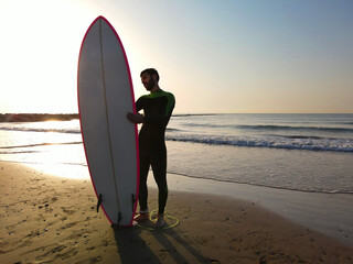 Fototapeta na wymiar MAN WITH A SURFBOARD ON THE BEACH