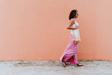 Obraz na płótnie Canvas woman walking by the city, holding a cotton bag with fruit. Eco friendly, zero waste concept