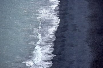 Waves of the Atlantic ocean fall on the black sand of the beach of Iceland from a height