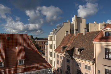 Early morning view of old houses roofs, windows, dormers, cornices, chimneys, chimney stacks chimney pots, towers, antennas in Old Town of Riga, Latvia.