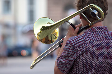 Fototapeta premium Reflection of the street in the instrument solo trumpet. male musician plays the trombone. music and creativity. jazz and Blues