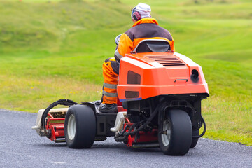 man rides on a special machine to clean the grass of the Golf course