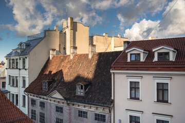 Fototapeta na wymiar Early morning view of old houses roofs, windows, dormers, cornices, chimneys, chimney stacks chimney pots, towers, antennas in Old Town of Riga, Latvia.
