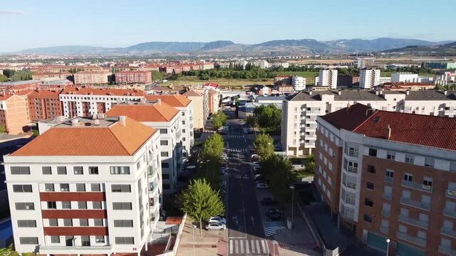 Vista a&eacute;rea de una rotonda en una ciudad con &aacute;rboles y c&eacute;sped avanzando hacia una calle entre edificios desde un parque. 