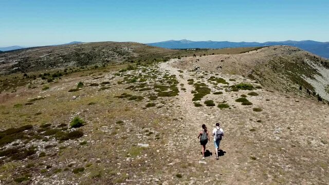 Vista a&eacute;rea de una pareja haciendo senderismo por un camino en una monta&ntilde;a.
