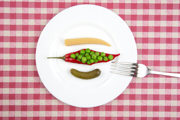 salad of pickled and pickled corn, peas, cucumber and red pepper on a white plate.  food and vegetables. diet and weight loss