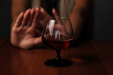 Young woman. alcoholic social problems concept. sitting refusal of alcohol. stop gesture. dark photo