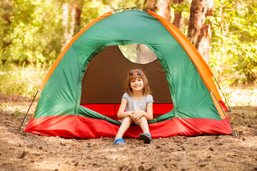 happy child girl enjoy summer time in camping tent in summer forest