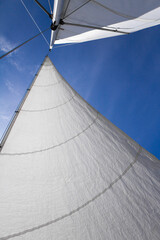 Bottom view of mast and sail of yacht on blue sky background, selective focus