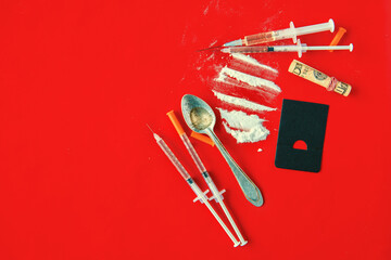 Hard drugs, syringe with vaccine, tablets and powder on red table 