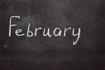 Fototapeta na wymiar Month written in white chalk on a chalkboard. The month depicted on the chalkboard is February