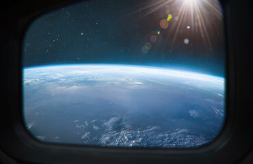View on Earth planet surface from ISS station porthole. Space and sun. Elements of this image furnished by NASA
