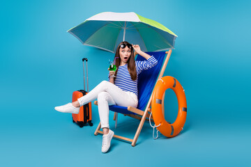 Portrait of her she nice attractive lovely amazed funky girl sitting in chair under parasol drinking mojito rest relax exotic tour isolated bright vivid shine vibrant blue color background © deagreez