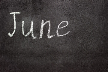Obraz premium Month written in white chalk on a chalkboard. The month depicted on the chalkboard is June