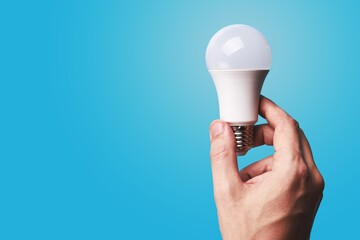 idea concept. caucasian male businessman holding white led bulb over blue background