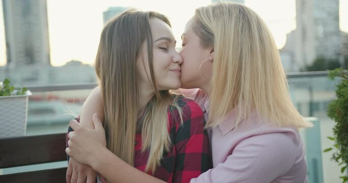 Happy loving homosexual lesbian LGBT couple kissing at city streets. Pride concept.