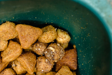 Dry Cat food in plastic bowl macro top view.
