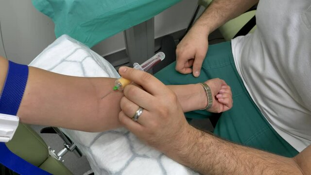 Close up view of a doctor and his female patient hand and arm in a laboratory taking blood sample in a test tube